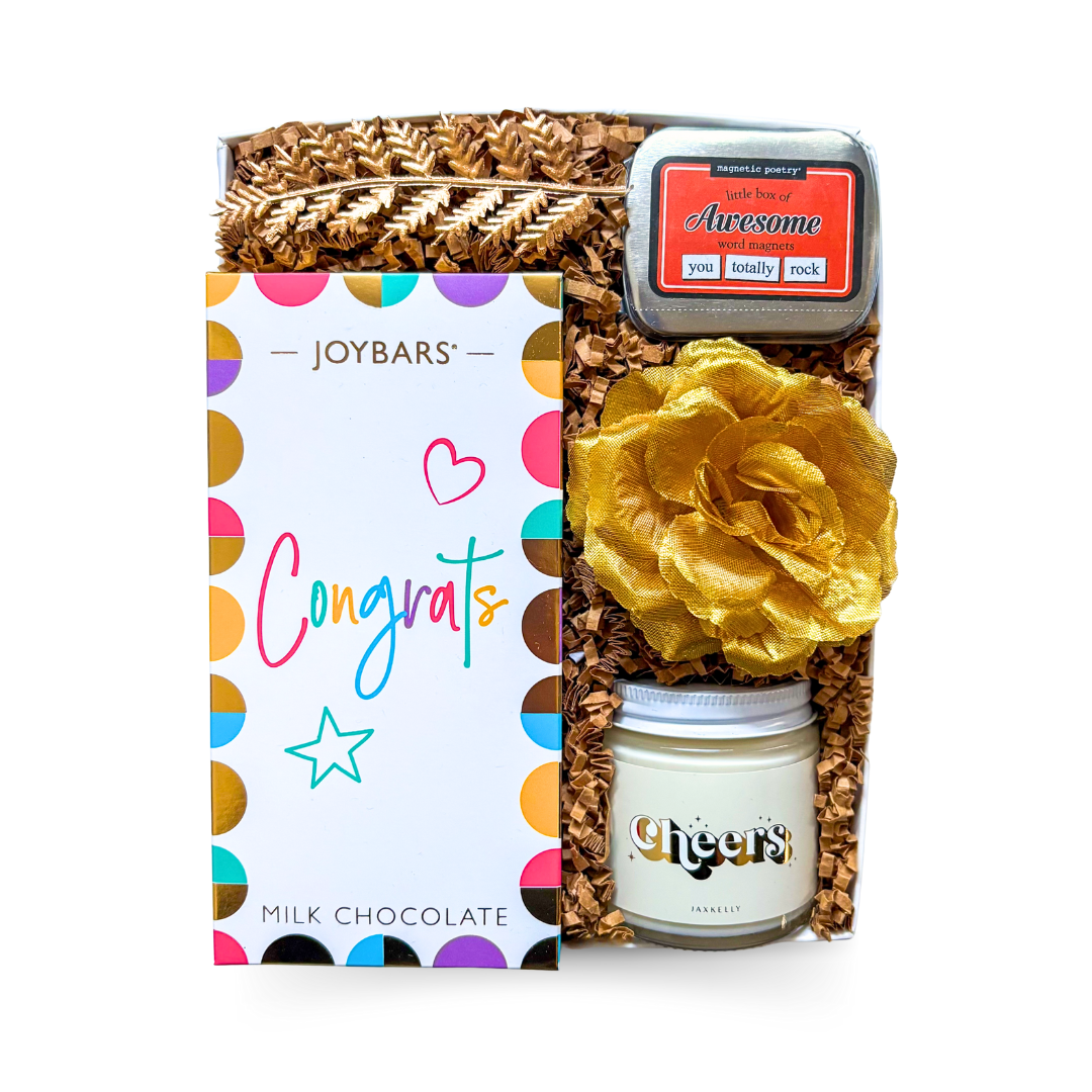The Congrats Box with vibrant chocolate bar, word magnets, and a candle or seed pack styled as a bright, modern celebration gift.