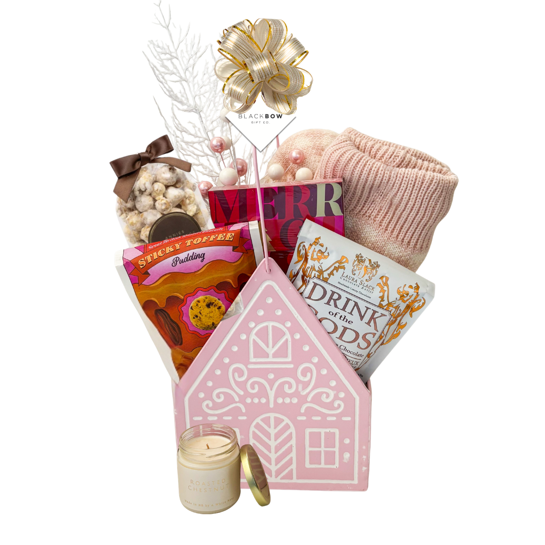 The Cozy Cottage gift basket featuring blush pink reading socks, roasted chestnut candle, gourmet chocolates, sweet treats and a pink cottage keepsake basket.