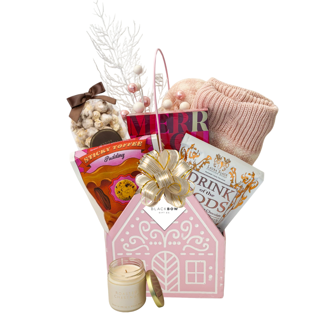 The Cozy Cottage gift basket featuring blush pink reading socks, roasted chestnut candle, gourmet chocolates, sweet treats and a pink cottage keepsake basket.