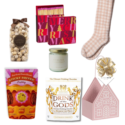 The Cozy Cottage gift basket featuring blush pink reading socks, roasted chestnut candle, gourmet chocolates, sweet treats and a pink cottage keepsake basket.