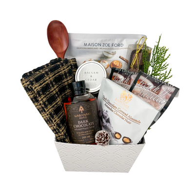 The Finer Things luxury gourmet gift basket featuring premium baking mix, chocolate treats, maple syrup, candle, wooden spoon and elegant kitchen textiles.