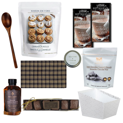 The Finer Things luxury gourmet gift basket featuring premium baking mix, chocolate treats, maple syrup, candle, wooden spoon and elegant kitchen textiles.