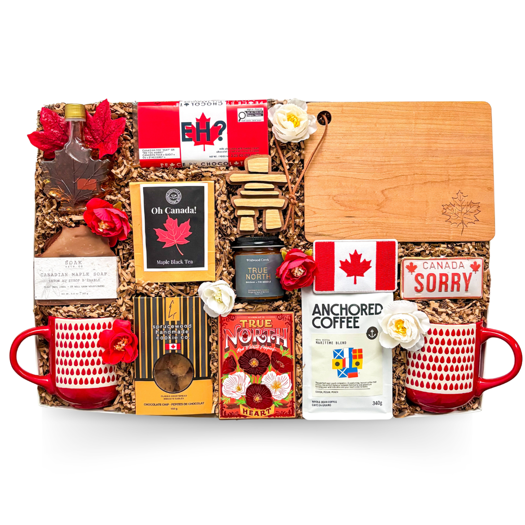 Luxury Canadian gift box featuring artisan coffee, pure Canadian maple syrup, pancake mix, maple black tea, artisan jam, maple soap, handcrafted cookies, Canadian mugs, engraved serving board, inukshuk décor, and premium Canadian-inspired keepsakes arranged in a layered presentation.