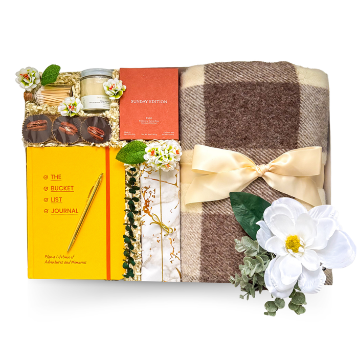 Luxury oversized high-gloss black magnetic gift box featuring a soft throw blanket, Pendleton journal, bucket list journal, candle, gourmet treats, mulled wine spices, wine glass, bookmark, optional book selections, and premium relaxation gifts.

