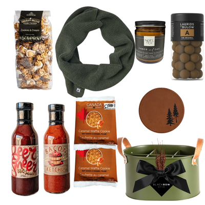 The Lodge Collection luxury gift basket featuring cozy knitwear, gourmet snacks, artisan sauces, a scented candle and leather accessories in an olive green metal keepsake caddy.