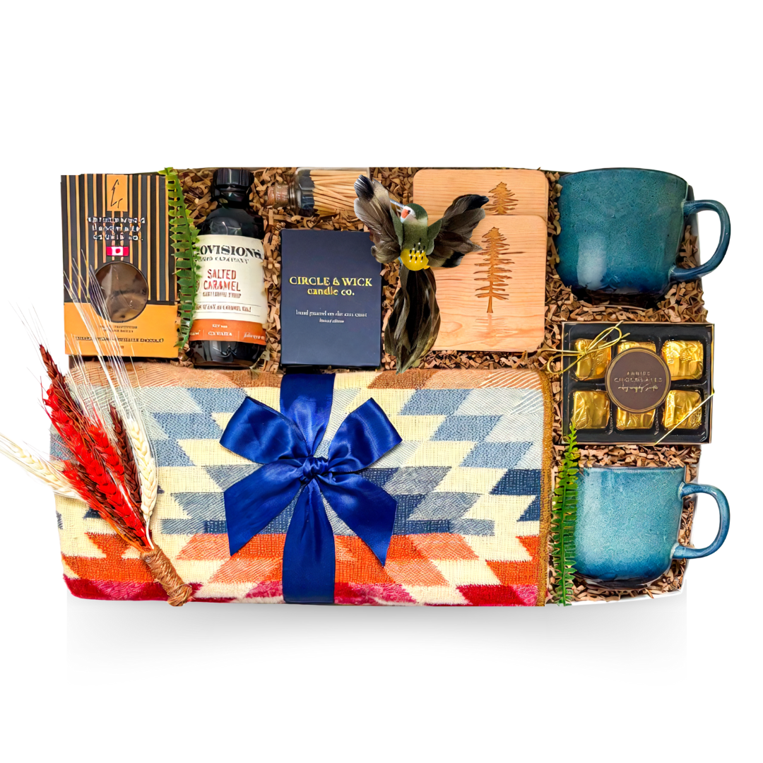 The Perfect Escape luxury gift box featuring a colourful woven throw blanket, two blue ceramic mugs, wooden coasters, candle, gourmet chocolates and treats.