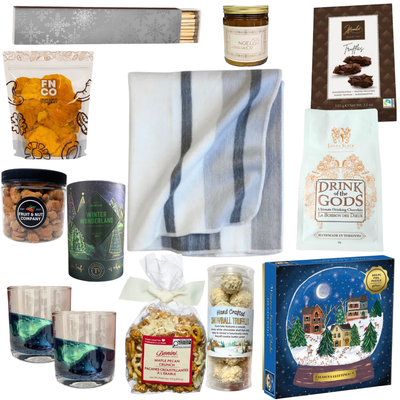 The Winter Escape luxury gift featuring a cozy blanket, elegant drinkware, gourmet chocolates, hot chocolate and artisan treats in a beautifully illustrated winter village gift package.