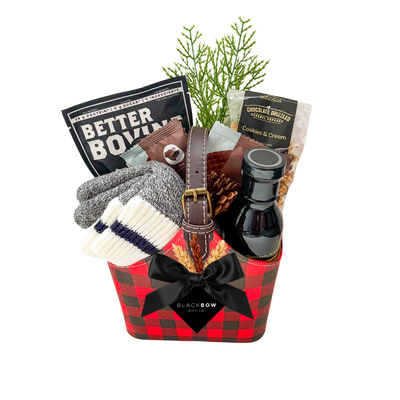 The Winter Explorer gift basket featuring a red and black buffalo plaid keepsake caddy filled with gourmet snacks, winter accessories and cozy wool gloves with an optional sock selection.