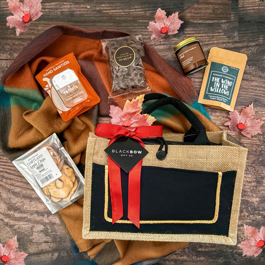 True North Comforts Canadian gift basket with a cozy fall scarf, candle, chocolate, apple crisps and maple-inspired treats presented in a reusable tote by Black Bow Gift Co.