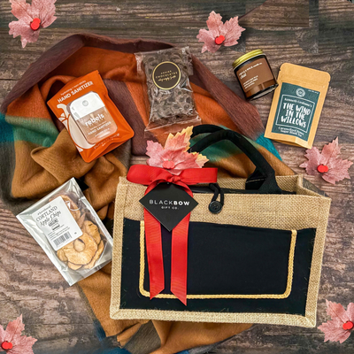 True North Comforts Canadian gift basket with a cozy fall scarf, candle, chocolate, apple crisps and maple-inspired treats presented in a reusable tote by Black Bow Gift Co.