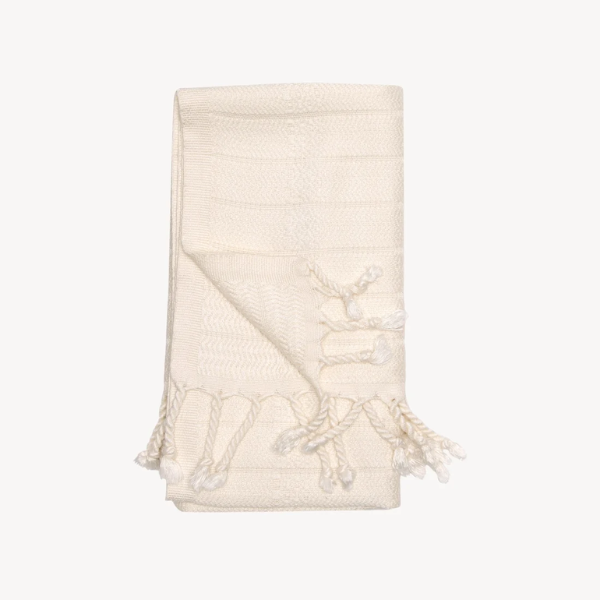 Cream hand towel with a soft textured weave, decorative fringe, and neutral design for bathroom styling.