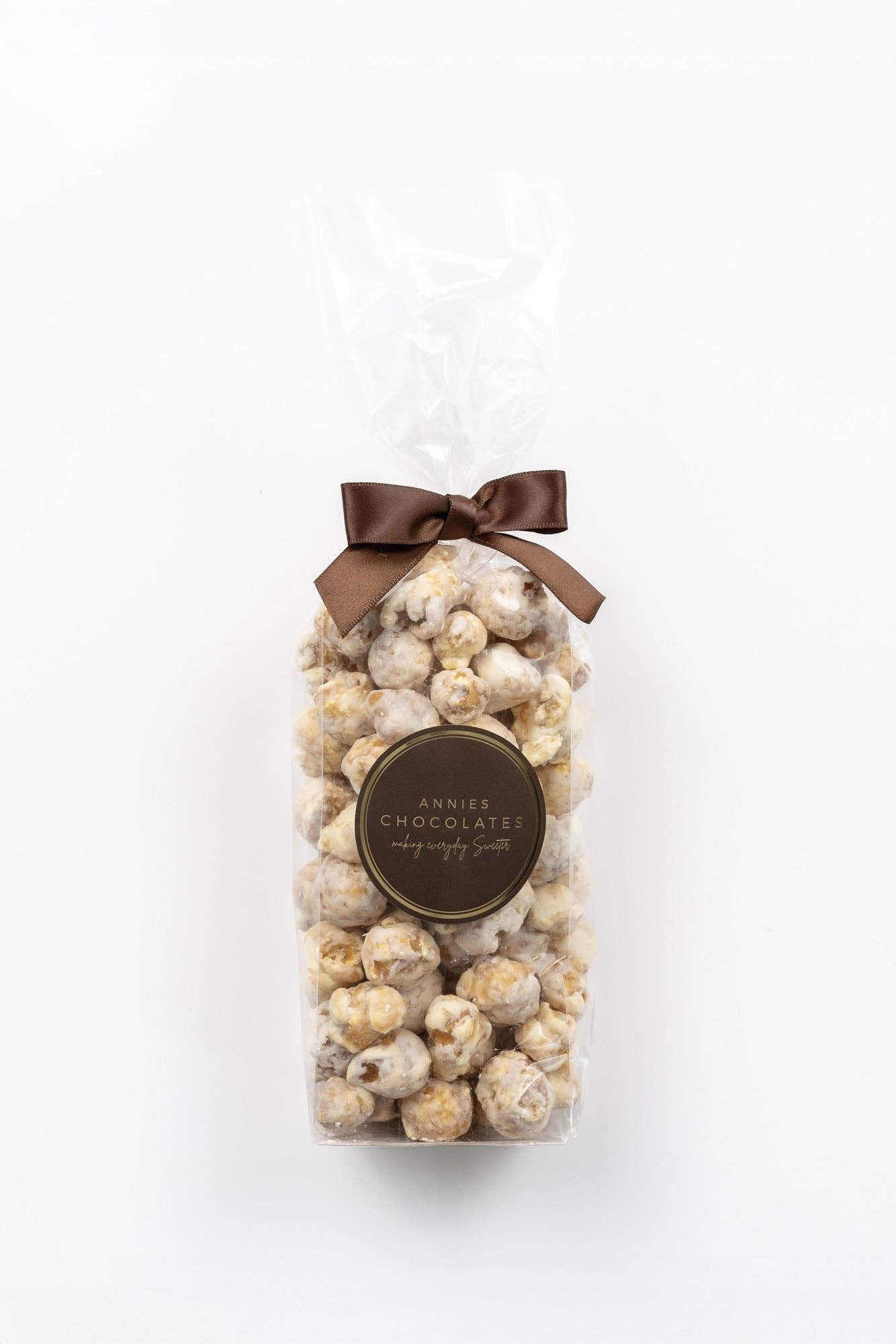White chocolate covered caramel corn in a clear pouch with a brown ribbon closure