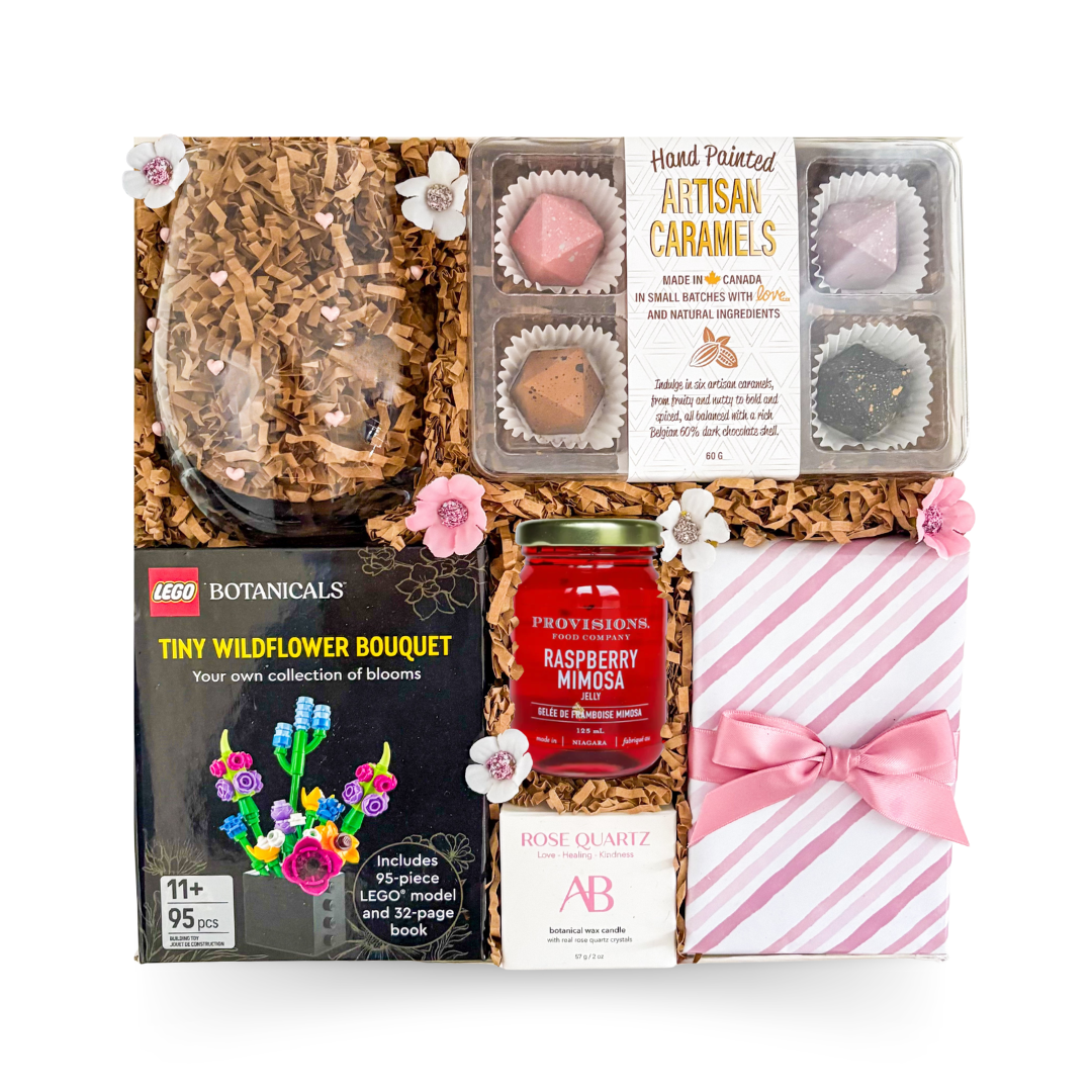 Luxury gift box featuring wildflower building kit, artisan caramels, rose quartz candle, raspberry mimosa jelly, heart-pattern stemless glass, and gourmet treats by Black Bow Gift Co.

