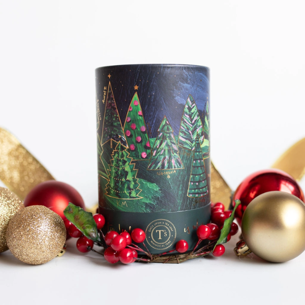 Winter Wonderland luxury loose leaf tea in a festive illustrated tin, surrounded by Christmas ornaments, red berries, and seasonal greenery.