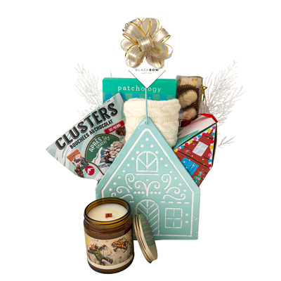 Winter Wonderland Christmas gift featuring cozy ivory fingerless gloves, candle, chocolates and festive treats in a light blue gingerbread house keepsake basket.