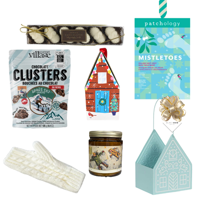 Winter Wonderland Christmas gift featuring cozy ivory fingerless gloves, candle, chocolates and festive treats in a light blue gingerbread house keepsake basket.