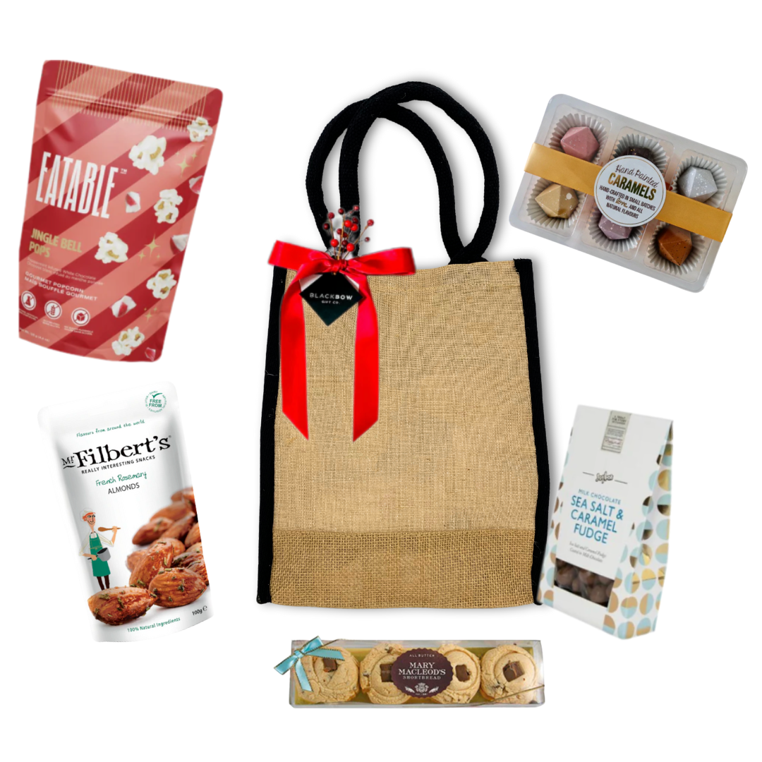 Gift bag with a red ribbon surrounded by various snacks on a white background