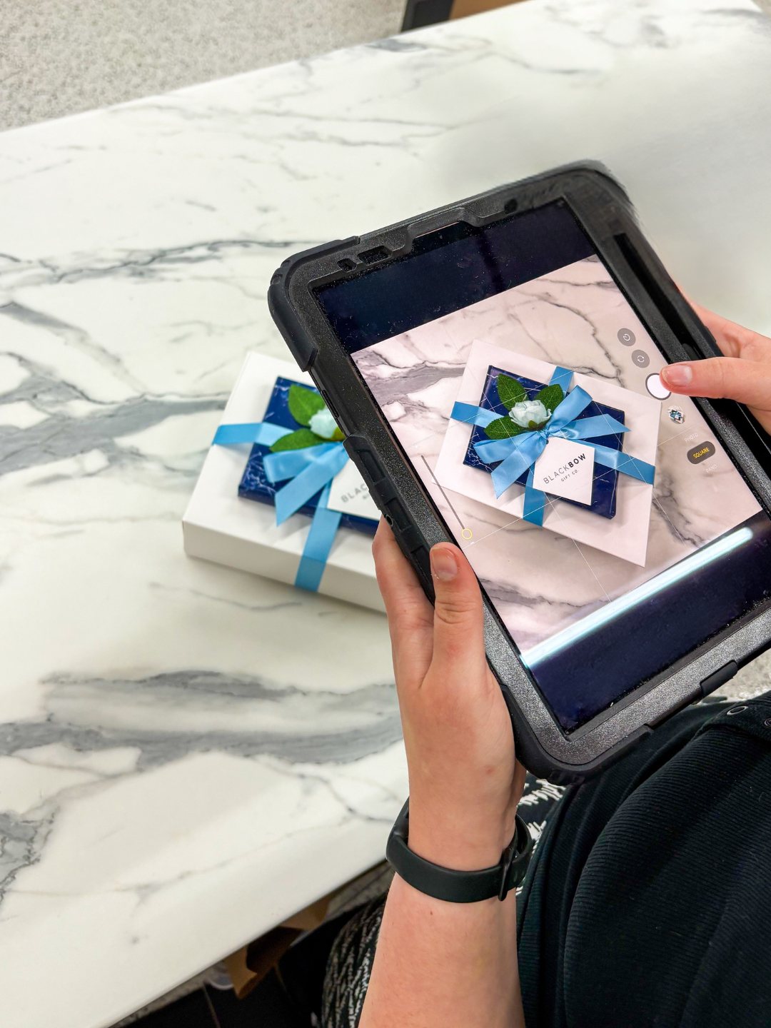 A team member photographing a finished gift on a tablet.