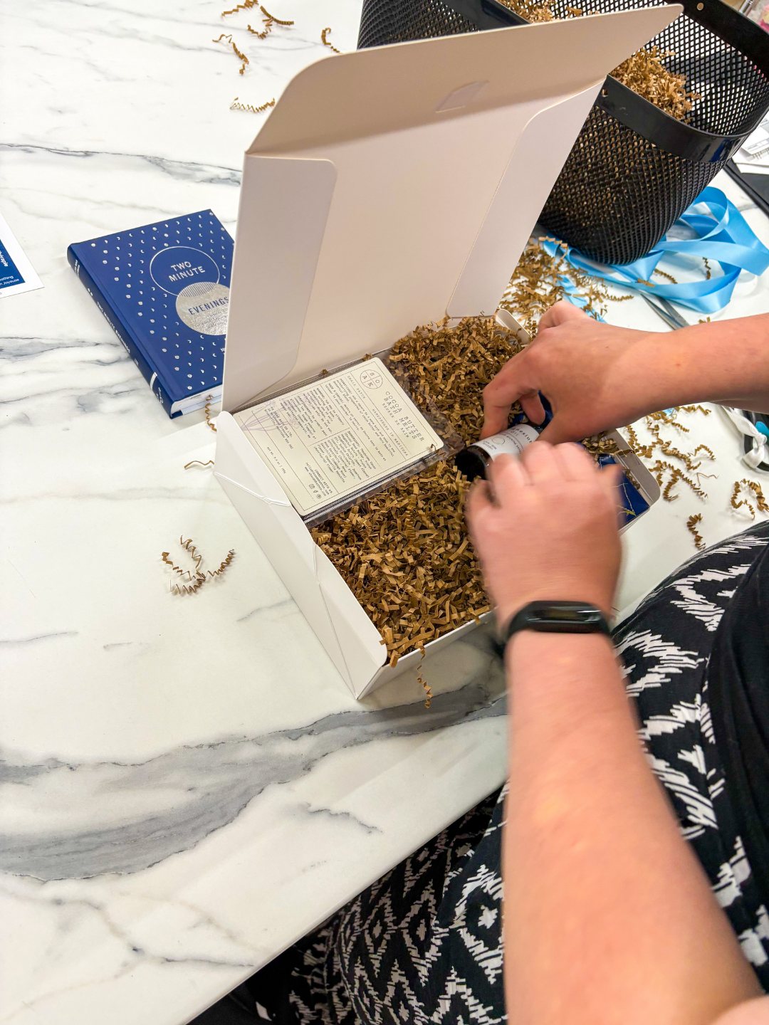 A team member placing a card into a gift box filled with crinkle paper.
