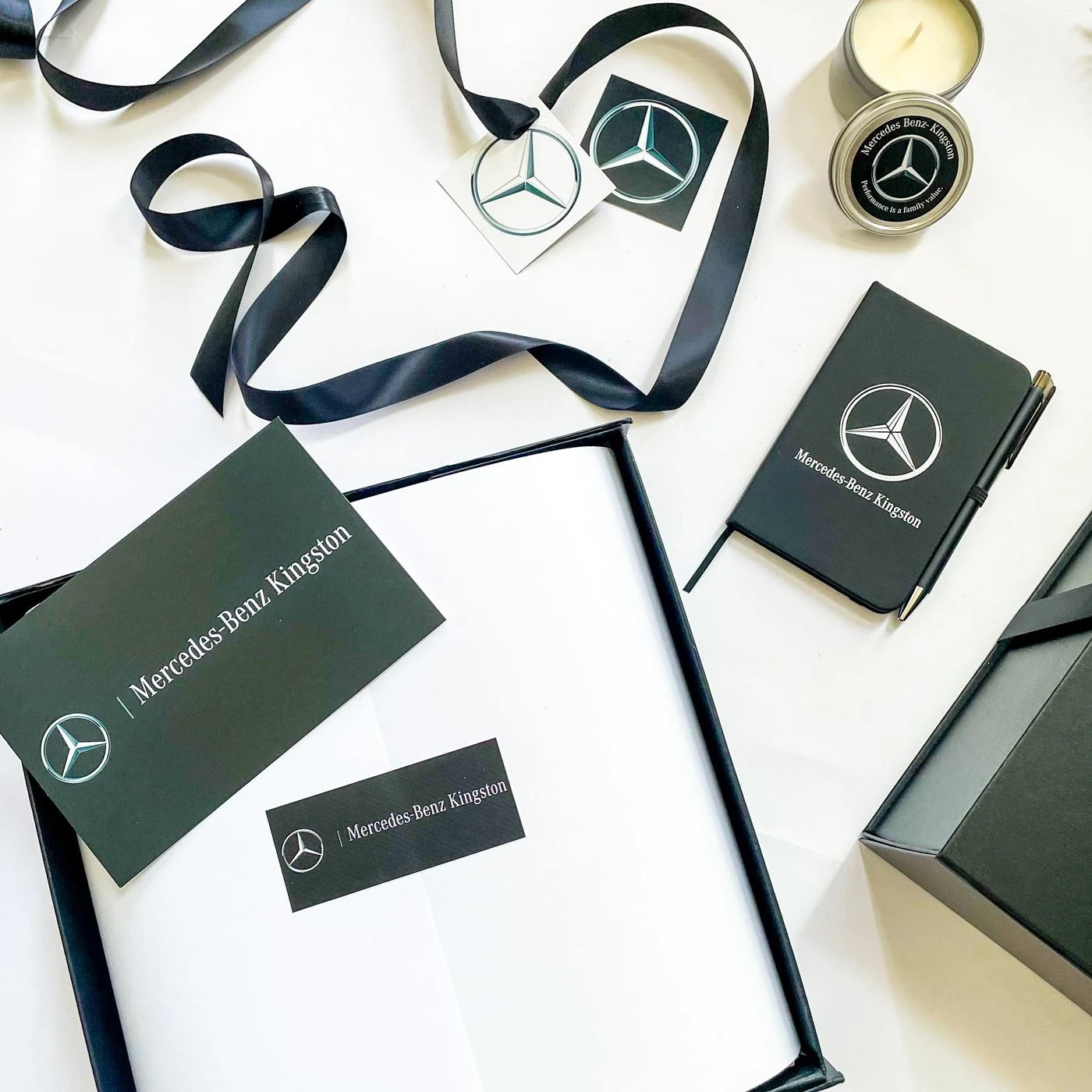 A Mercedes-Benz Kingston gift set: branded notebook, candle, coasters and cards with black ribbon.