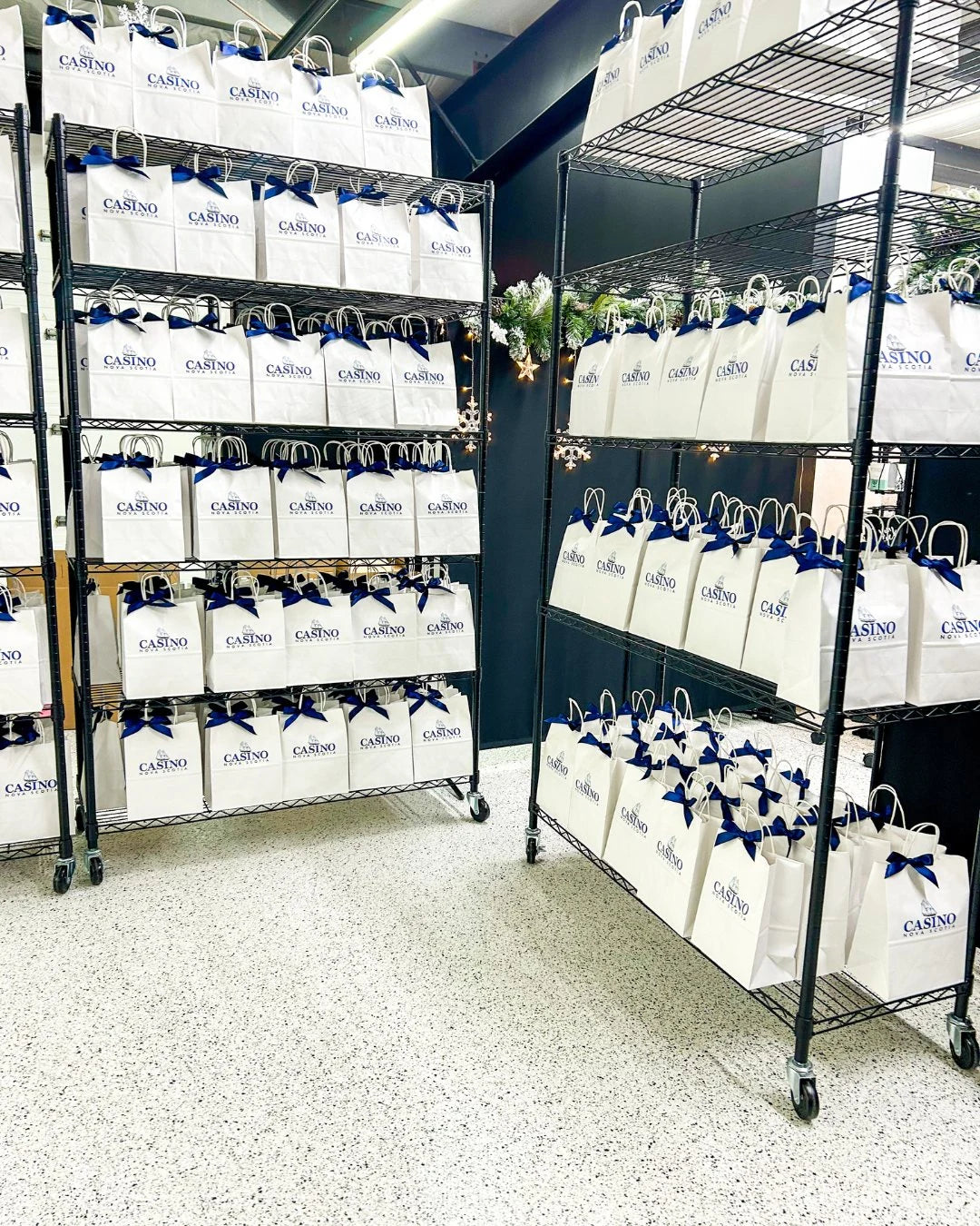 Racks of white branded gift bags staged in the Black Bow studio.